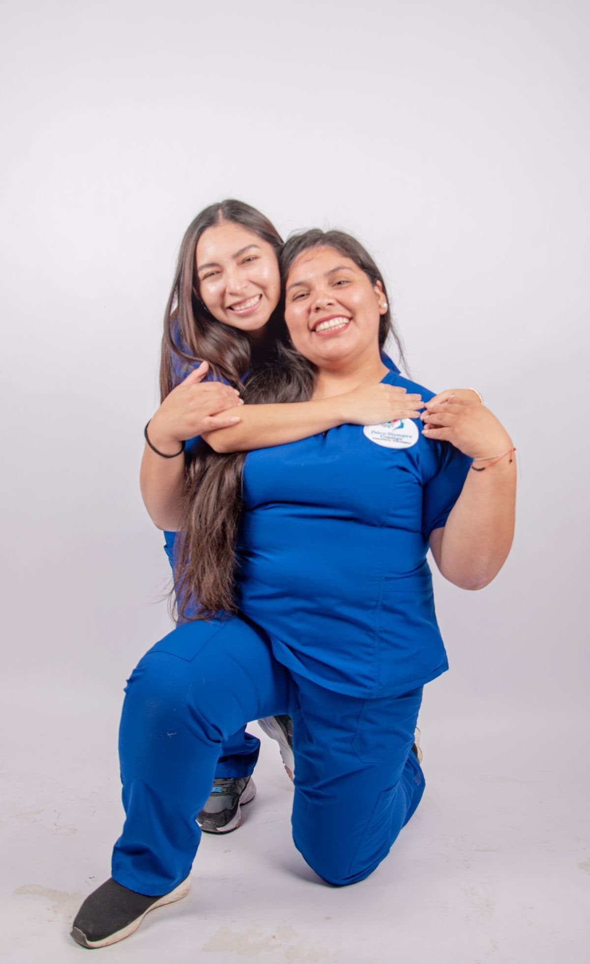 Two nurses embracing, celebrating a friend joining